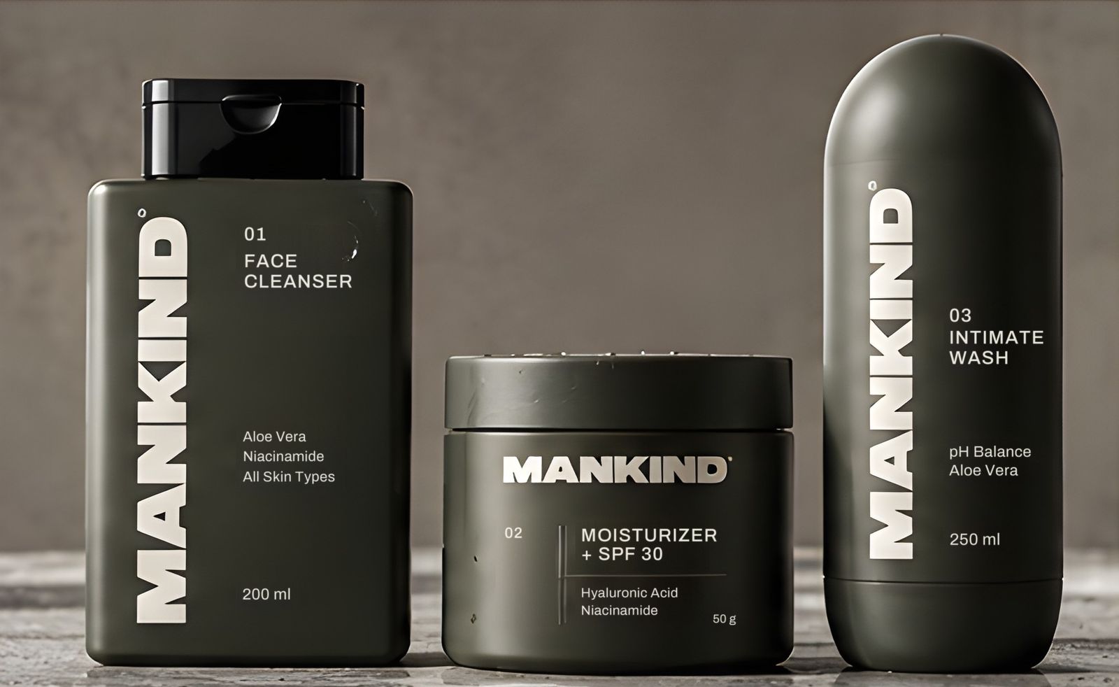 The First Kit de MANKIND sobre piedra: Cleanser en botella rectangular, Moisturizer + SPF 30 en pote y Intimate Wash en botella alargada. Render de referencia.